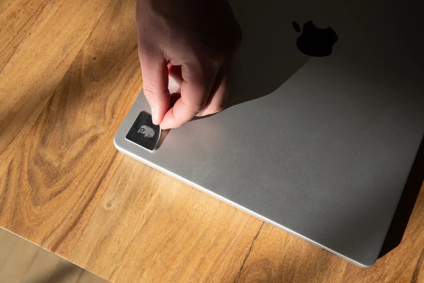 A hand peeling a reusable screen cleaner from a laptop