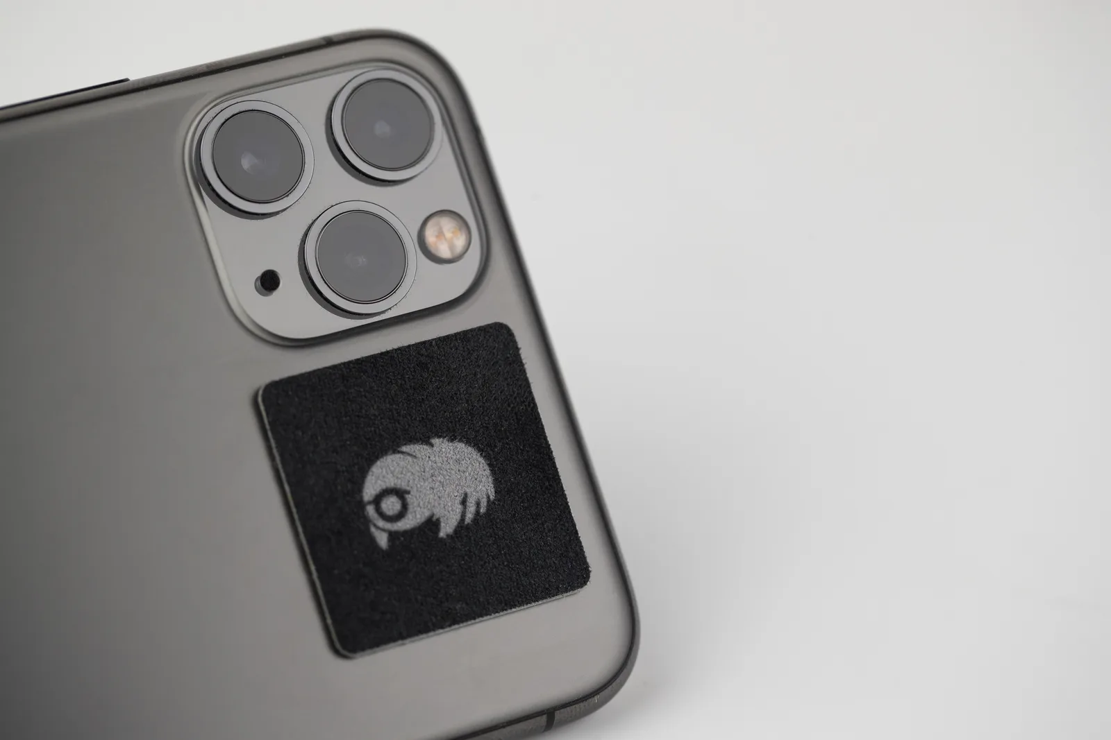 A square microfiber screen cleaner attached beside a phone camera