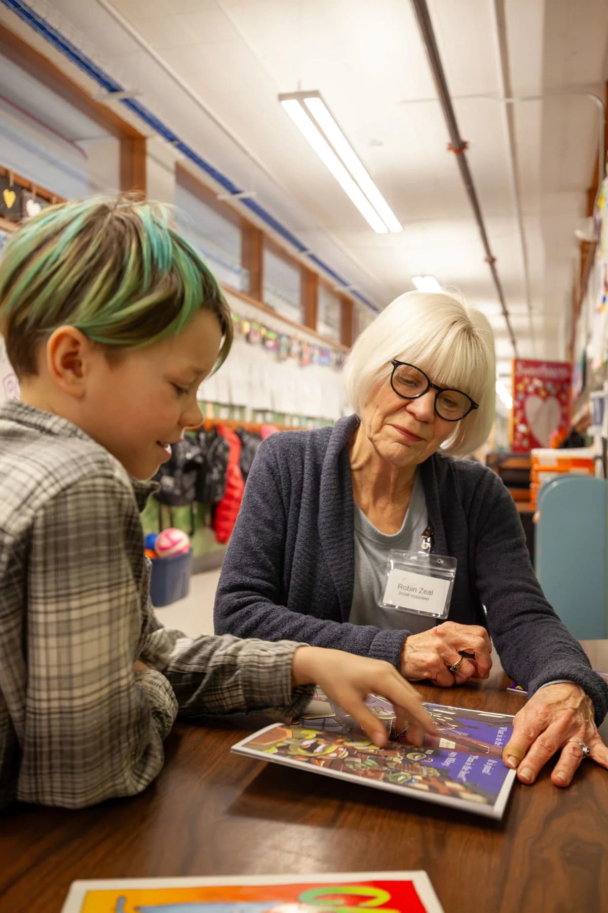 A volunteer and student reading together in a classroom
