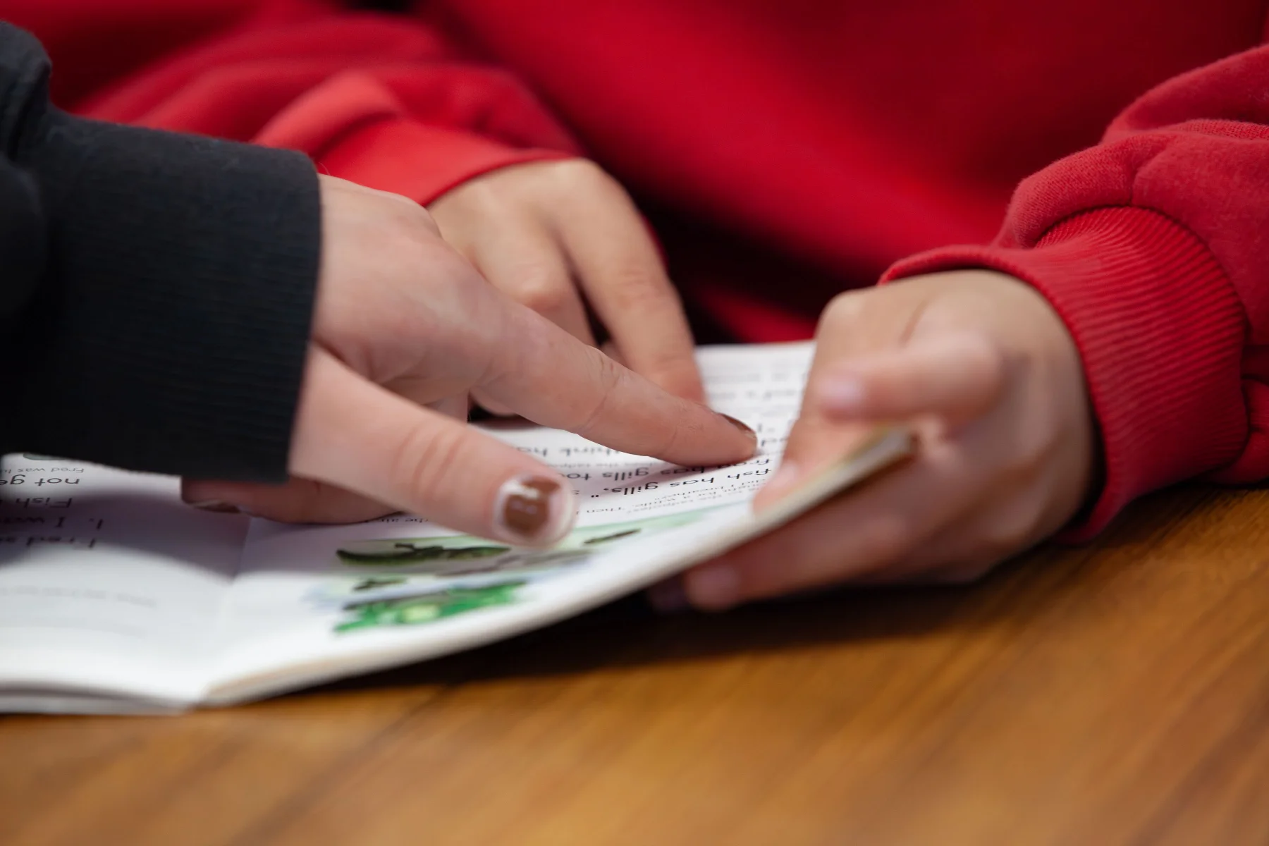 A volunteer guiding a student through words on a page